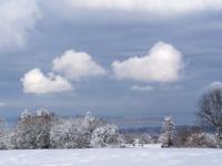 Weiße Wolkenhaufen am grauem Himmel und winterlicher Chiemseeblick